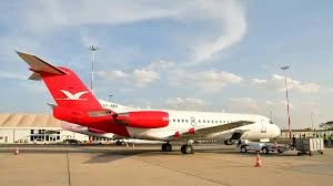 Skyward jet with its red branded tail parked beside airport facilities