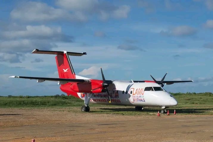 Skyward Express Dash 8 in Lamu Festivals livery parked on a coastal airstrip under a blue sky